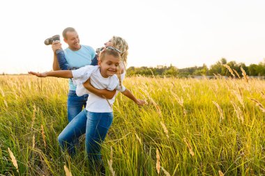 Yürüyüş ve yeşil alana günbatımında eğleniyor oğlu ile genç Aile