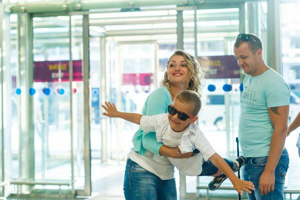 Young family with son having fun in airport before departure 