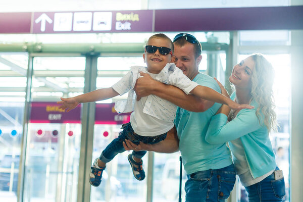 Young family with son having fun in airport before departure 