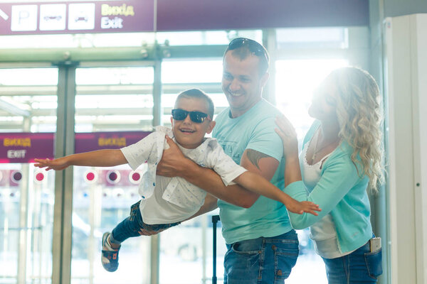 Young family with son having fun in airport before departure 