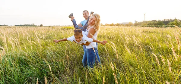 若い家族は歩いて 日没時緑の野原で良い時間を過ごしての息子と — ストック写真
