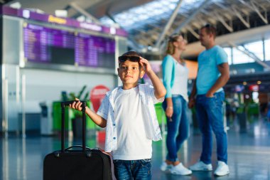 Sevimli küçük çocuk ile anne ve Havaalanı salonu ile bavul ayakta