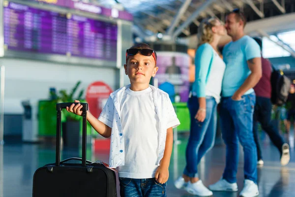 Sevimli küçük çocuk ile anne ve Havaalanı salonu ile bavul ayakta