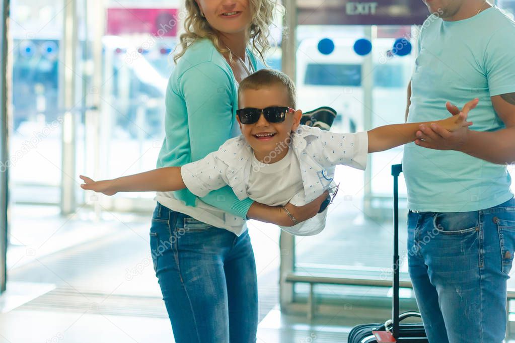 Family traveling with kids. Parents with children at international airport with luggage. A boy in the arms of his parents flies to a airport. Travel with child for summer vacation.