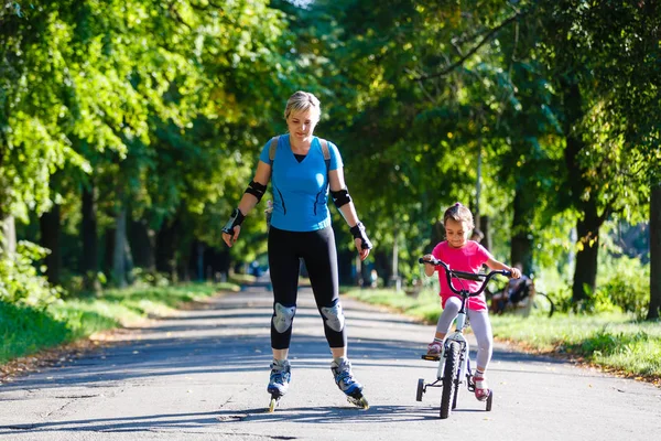 Madre Joven Patinaje Sobre Ruedas Con Hija Pequeña Montar Bicicleta — Foto de Stock