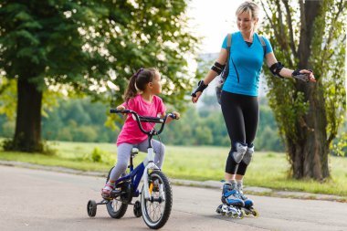 Genç Anne ile küçük kızı binicilik bisiklet park paten