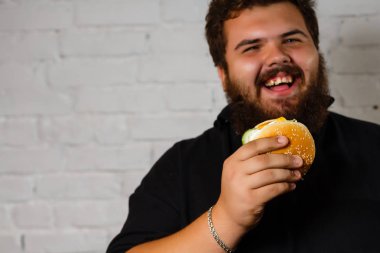 Bir koltukta oturan ve hamburgeri seyir şişman adam