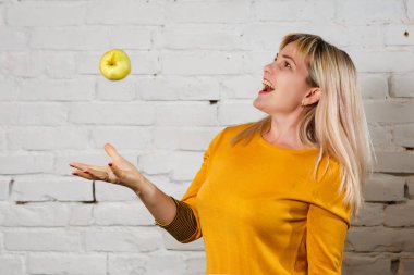 Tuğla duvarın yanında yeşil elmalı güzel bir kadın