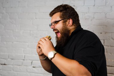 Şişman adam iştahla yemek Hamburger beyaz tuğla duvar arka plan üzerinde