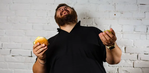 Homem Barbudo Excitado Gananciosamente Comendo Hambúrgueres Segurando Maçã Verde Outra — Fotografia de Stock