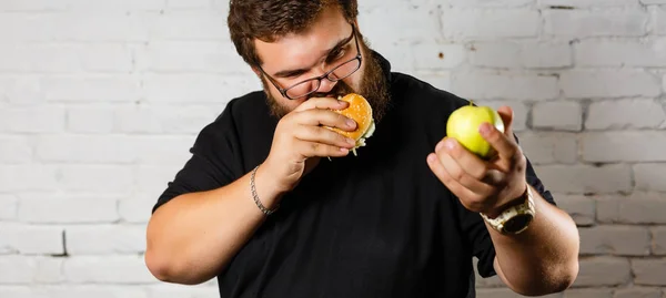 Eccitato Uomo Barbuto Avidamente Mangiare Hamburger Tenendo Mela Verde Altra — Foto Stock