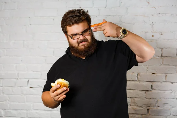 Hombre Gordo Comiendo Hamburguesa Codiciosamente Sobre Fondo Pared Ladrillo Blanco — Foto de Stock