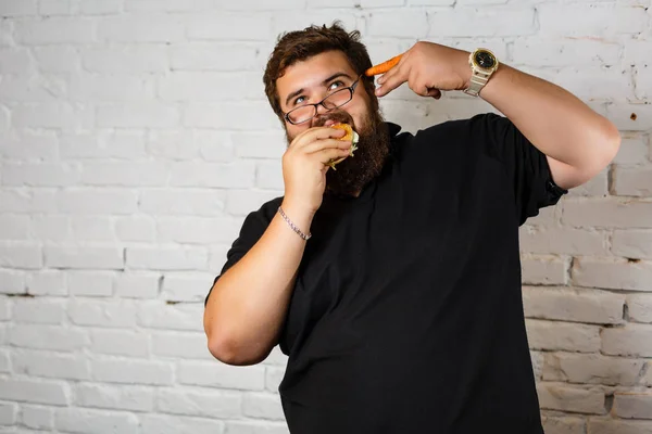 Kövér Ember Mohón Eszik Hamburgert Fehér Téglafal Háttér — Stock Fotó