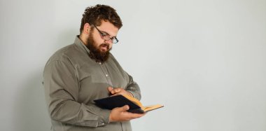 gri arka plan üzerinde duran kitap okurken erkek öğrenci portresi