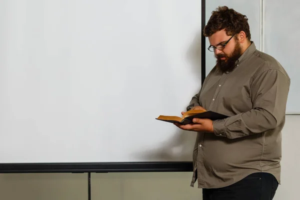 白い背景の上の本を保持している眼鏡の脂肪の若い男 — ストック写真