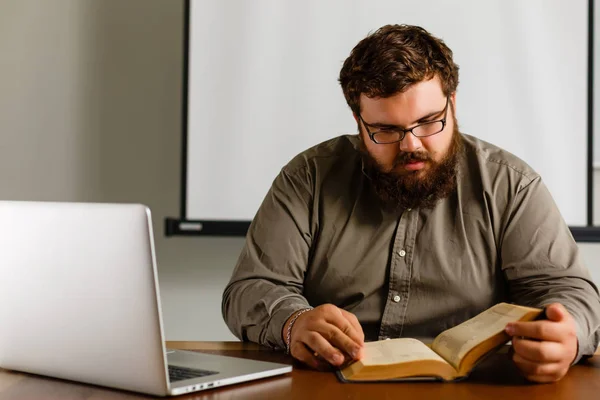 Nachdenklicher Europäischer Geschäftsmann Liest Buch Schreibtisch Mit Laptop — Stockfoto