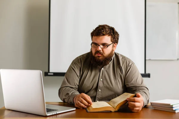 Nachdenklicher Europäischer Geschäftsmann Liest Buch Schreibtisch Mit Laptop — Stockfoto