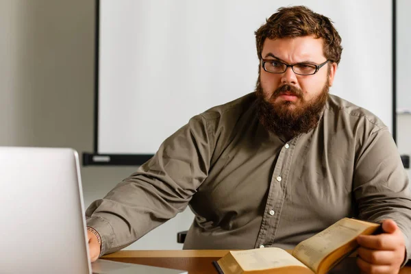 Nachdenklicher Europäischer Geschäftsmann Liest Buch Schreibtisch Mit Laptop — Stockfoto