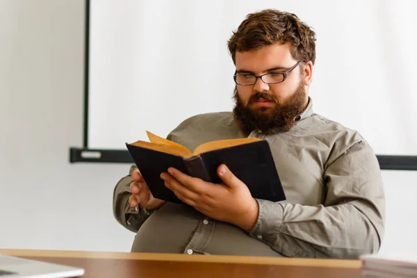 Ernstige Bebaarde Man Leesboek Aan Tafel — Stockfoto