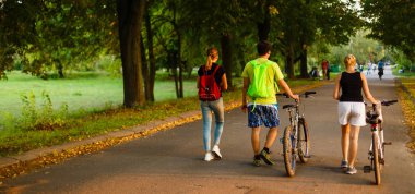 Bir grup insan yol boyunca bisikletle gider.