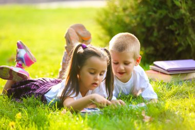 Erkek ve kız parkta yeşil arka plan üzerinde yalan