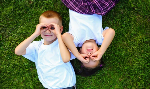 Yaz eğlencesi. birlikte yeşil çim üzerinde yalan ise gülen surat ve iki sevimli küçük çocuk Üstten Görünüm