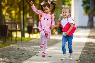 Two beautiful little girls going to school holding hands. Back to school clipart