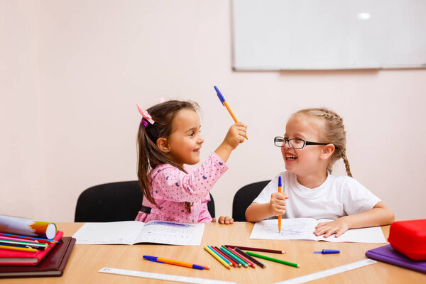 Милые маленькие девочки пишут ручкой в школе
