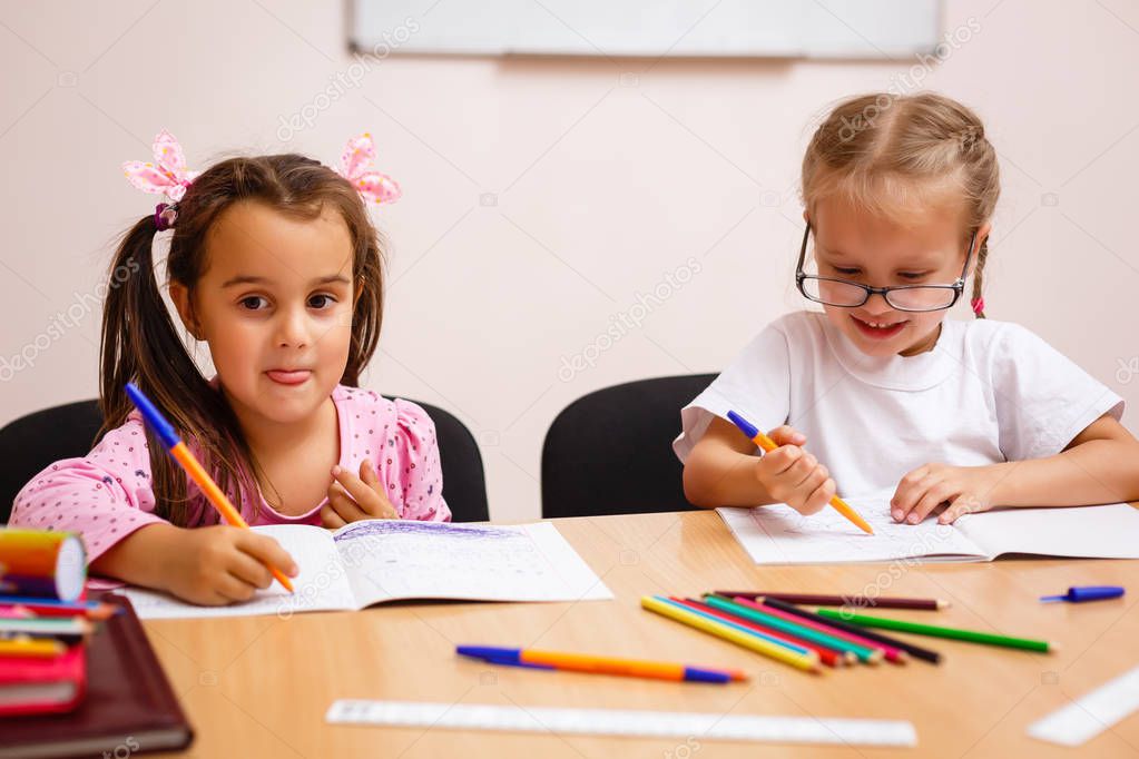 Cute little girls writing using a pen in school