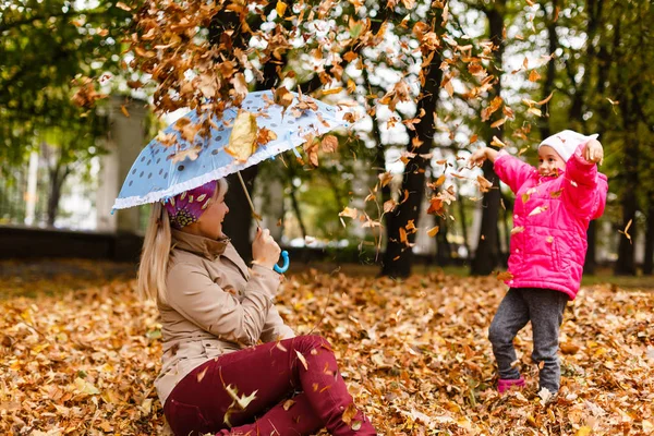 Kobieta Szczęśliwa Trzymając Parasol Zabawy Jej Małą Córeczkę Grając Jesiennych — Zdjęcie stockowe