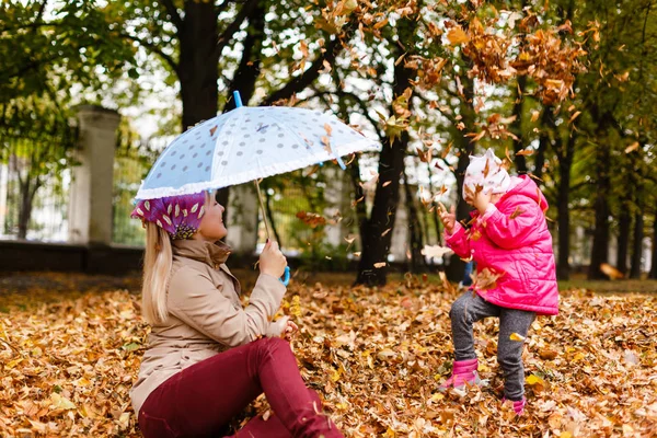 Kobieta Szczęśliwa Trzymając Parasol Zabawy Jej Małą Córeczkę Grając Jesiennych — Zdjęcie stockowe