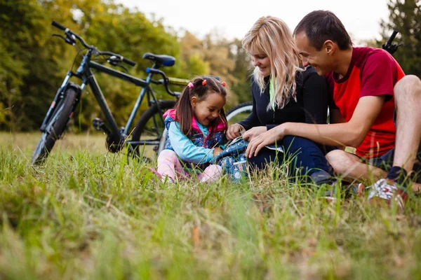 Active family resting on green grass after cycling