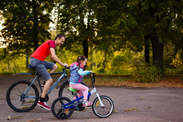 Gelukkig Jonge Vader Zijn Dochtertje Paardrijden Fietsen Groen Park Zijaanzicht — Stockfoto