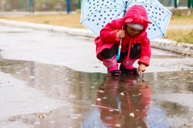 Su birikintisine açık havada sonbahar yağmurlu gün oynamak renkli şemsiye ile sevimli küçük kız 
