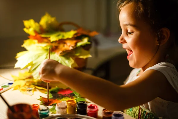 Χαριτωμένο Μικρό Κορίτσι Ζωγραφική Φθινοπωρινά Φύλλα Κάθεται Στο Τραπέζι — Φωτογραφία Αρχείου
