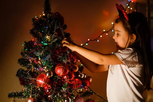 小さな女の子がカラフルなガラスの泡でクリスマスツリーを飾る — ストック写真