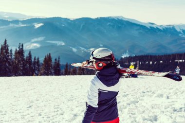 Dağ tepesinin tepesinde duran kadın kayakçı