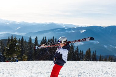 Dağ tepesinin tepesinde duran kadın kayakçı