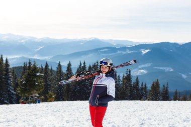 Dağ tepesinin tepesinde duran kadın kayakçı