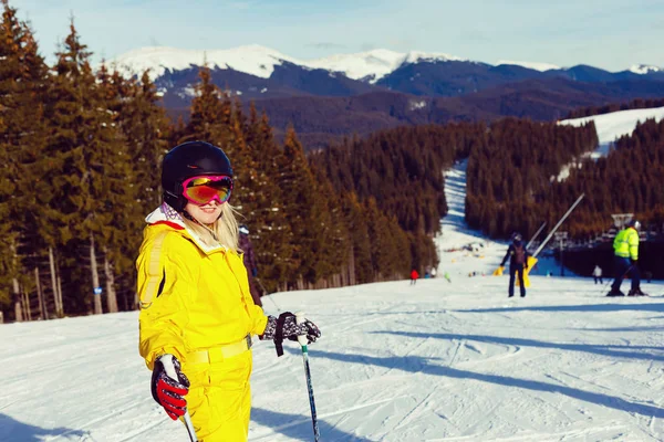 穿着黄色滑雪服的快乐女人躺在白雪上 — 图库照片
