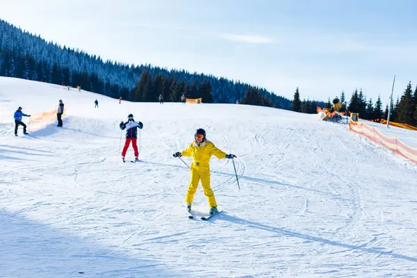 雪山でスキーに乗って黄色冬ジャンプ スーツの女性 — ストック写真