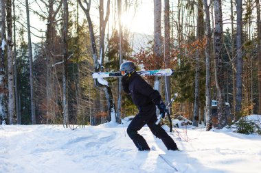 Beyaz kar üzerinde dinlenmiş siyah kayak takım elbiseli mutlu adam
