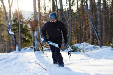 Beyaz kar üzerinde dinlenmiş siyah kayak takım elbiseli mutlu adam