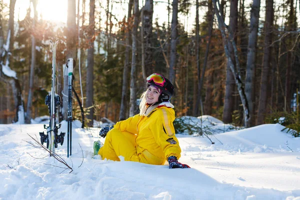 穿着黄色滑雪服的快乐女人躺在白雪上 — 图库照片