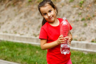 Küçük kız süt şişesinden su içiyor.