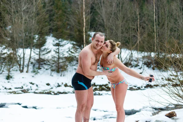 Young cheerful couple refreshing after hot-tub in snowy forest
