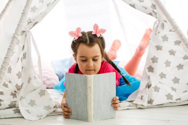 Evde rahat oturma odasında kitap okuma güzel küçük kız Portresi