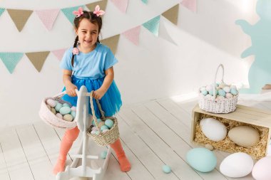 Paskalya oynarken küçük neşeli kız oturma odası dekore edilmiştir.