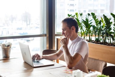 Kafede dizüstü bilgisayarda çalışan genç işadamı.