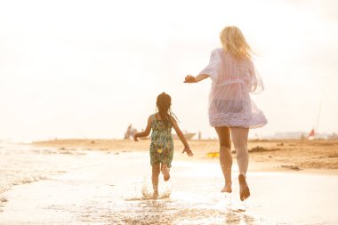 Genç anne ve kızı kumsalda eğleniyorlar. 